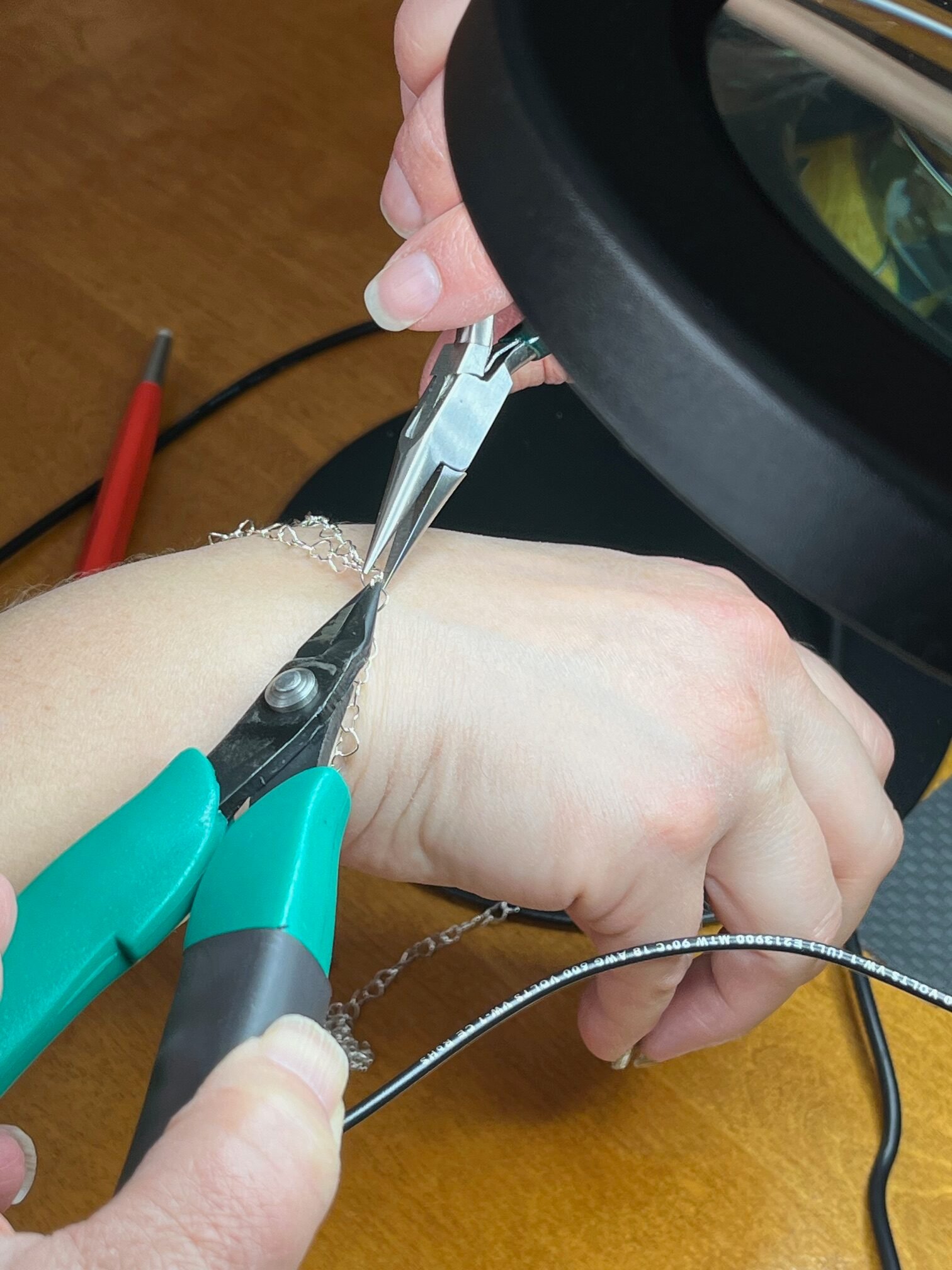Tricia closing a silver bracelet under a magnifying lamp
