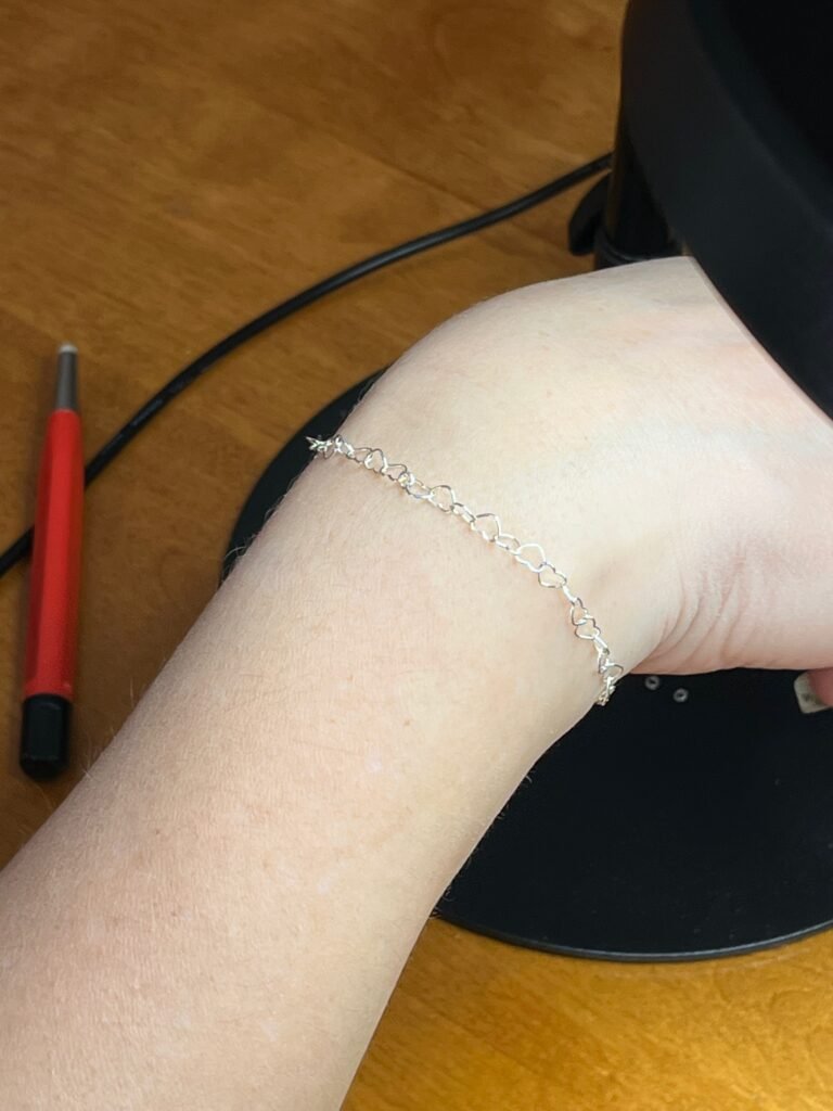 A delicate permanent bracelet fitted to a customer’s wrist