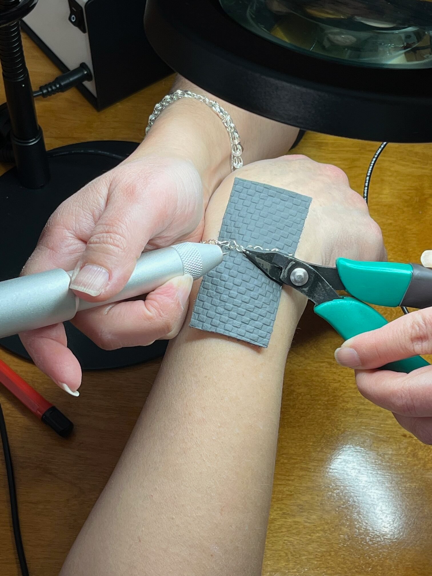 Pliers closing a silver permanent bracelet around a wrist