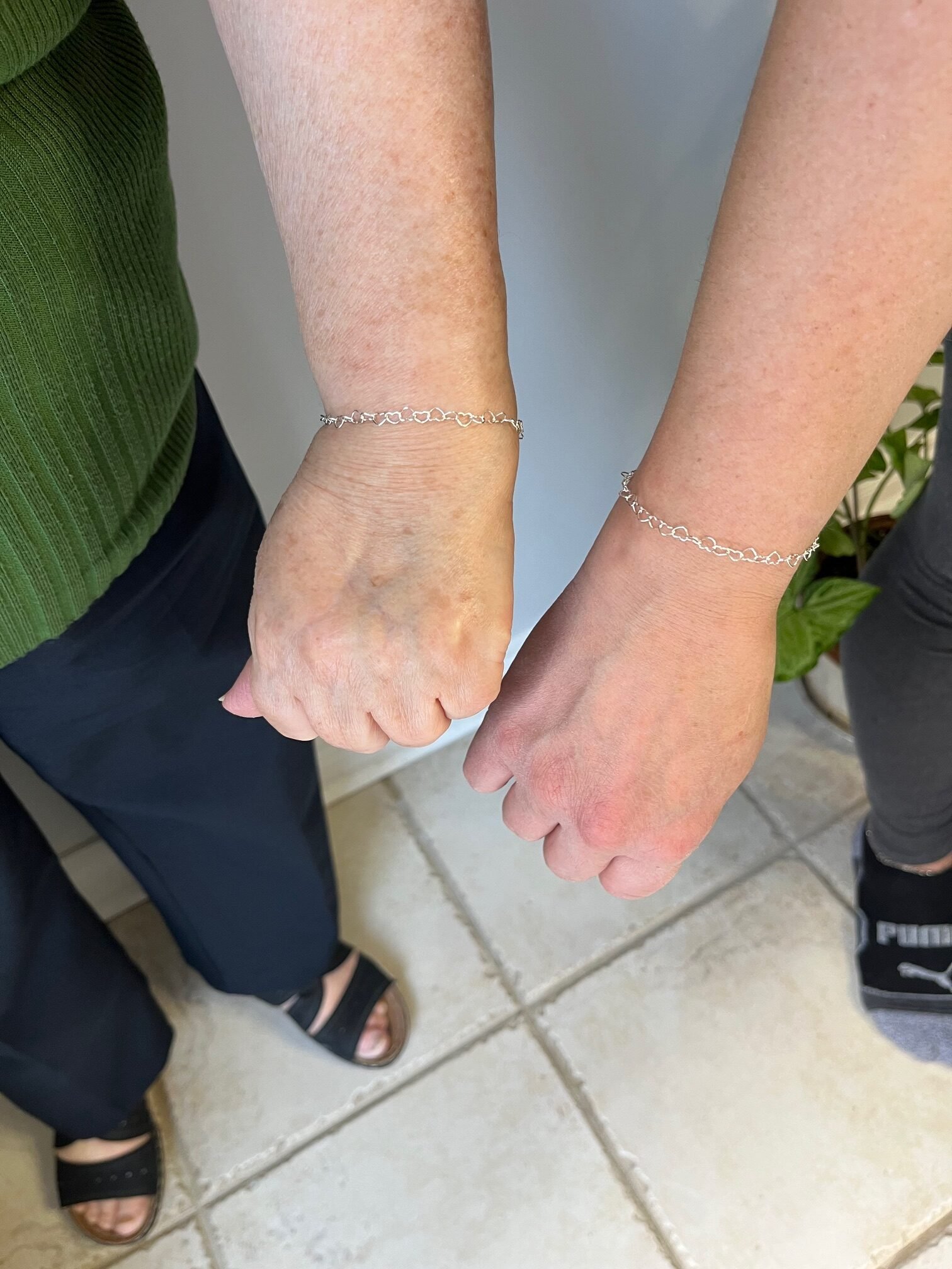 Two people showing their matching silver bracelets