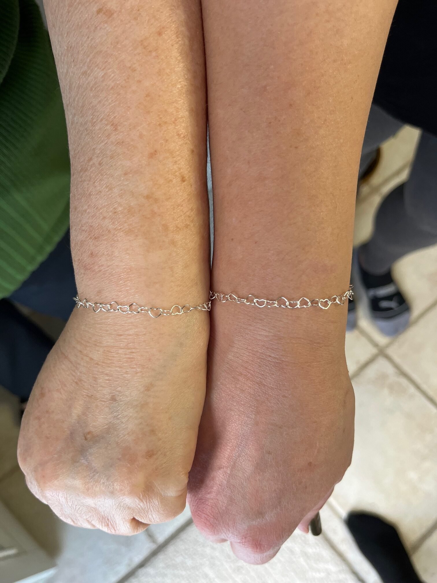 Matching silver heart-link bracelets worn together