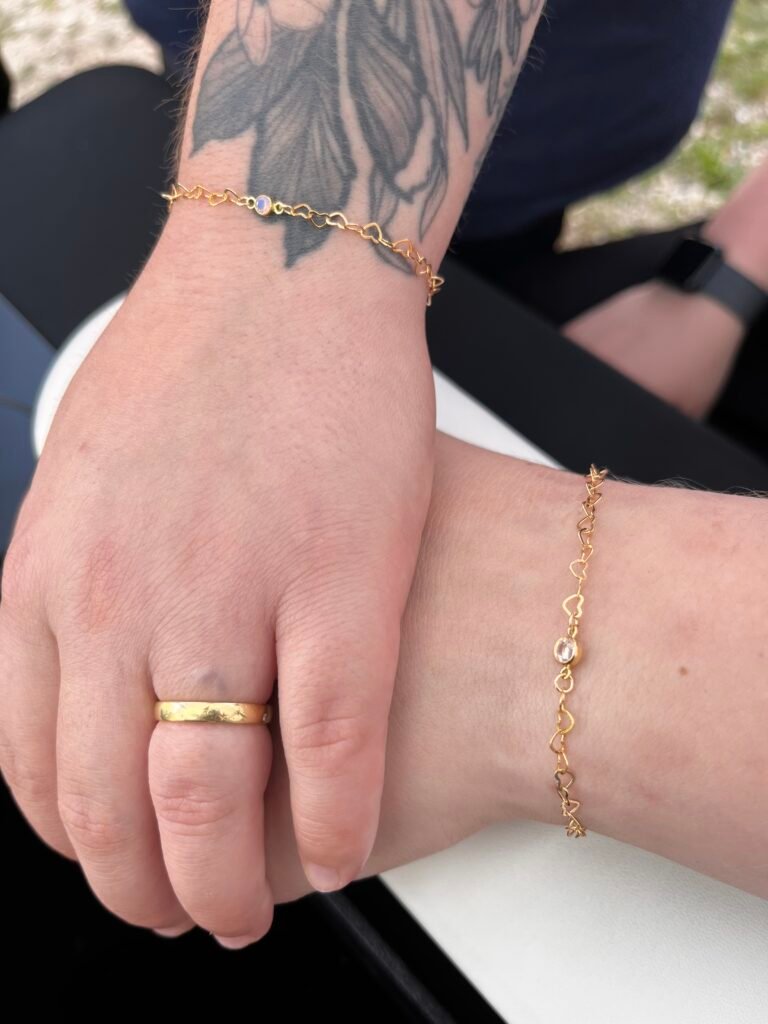 Matching gold heart-link bracelets on two wrists