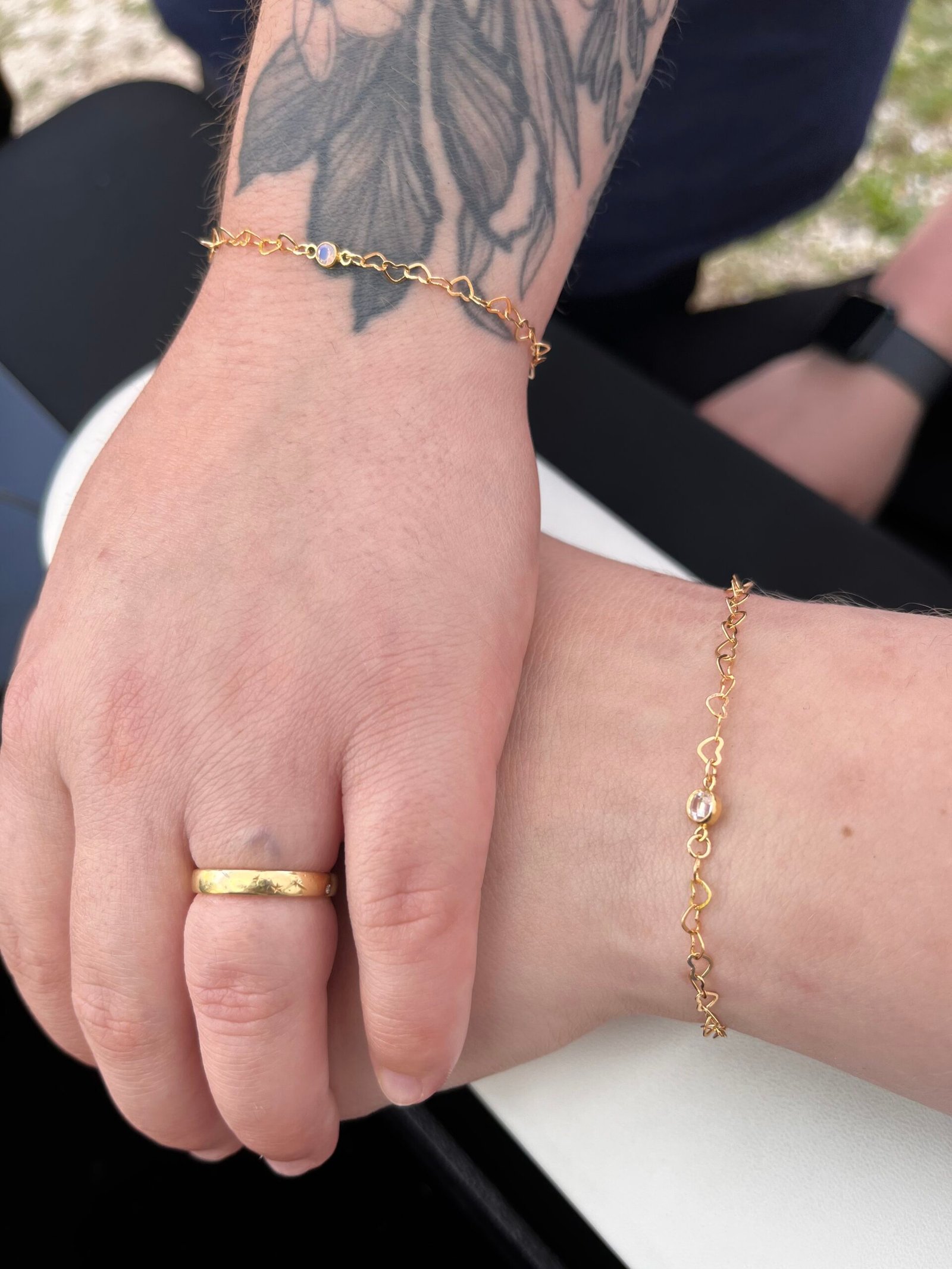 Matching gold heart-link bracelets on two wrists